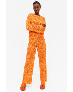 Plissierte orangefarbene Hose mit ungesäumten Beinabschlüssen Orangefarbenes Wirbelmuster
