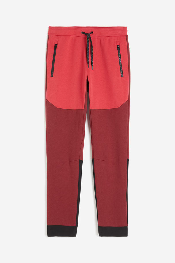 H&M DryMove™ Tapered Tech-Joggpants mit Zippertaschen Dunkelrot/Blockfarben