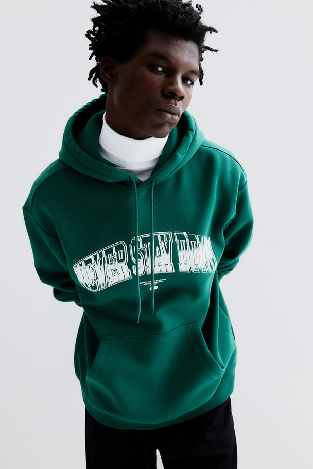 H&M Bedruckter Hoodie in Oversized Fit Grün/Never Stay Down